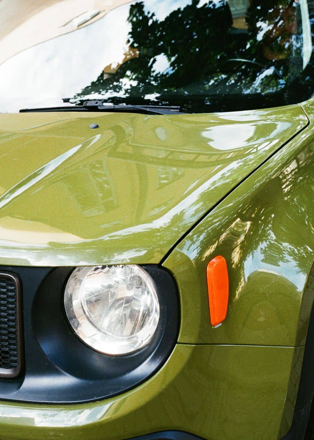 Närbild på framljus och motorhuv på grön bil utan lackskador