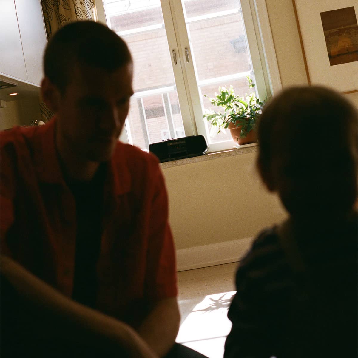 Två personer i motljus sitter i sitt kök