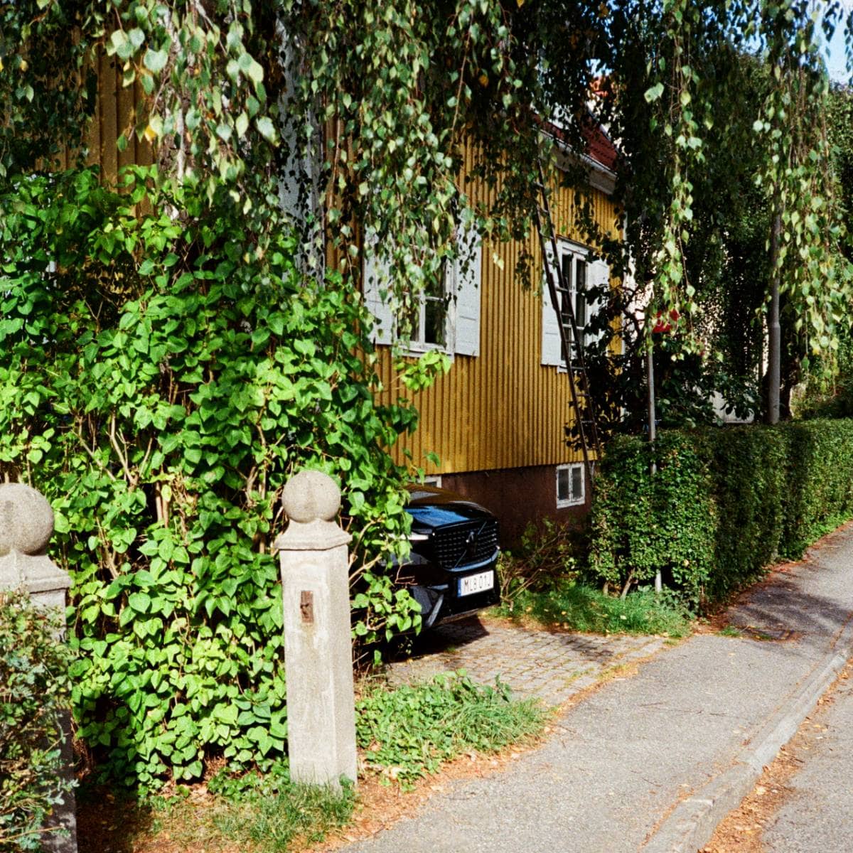 Nosen på en svart bil parkerad utanför en villa
