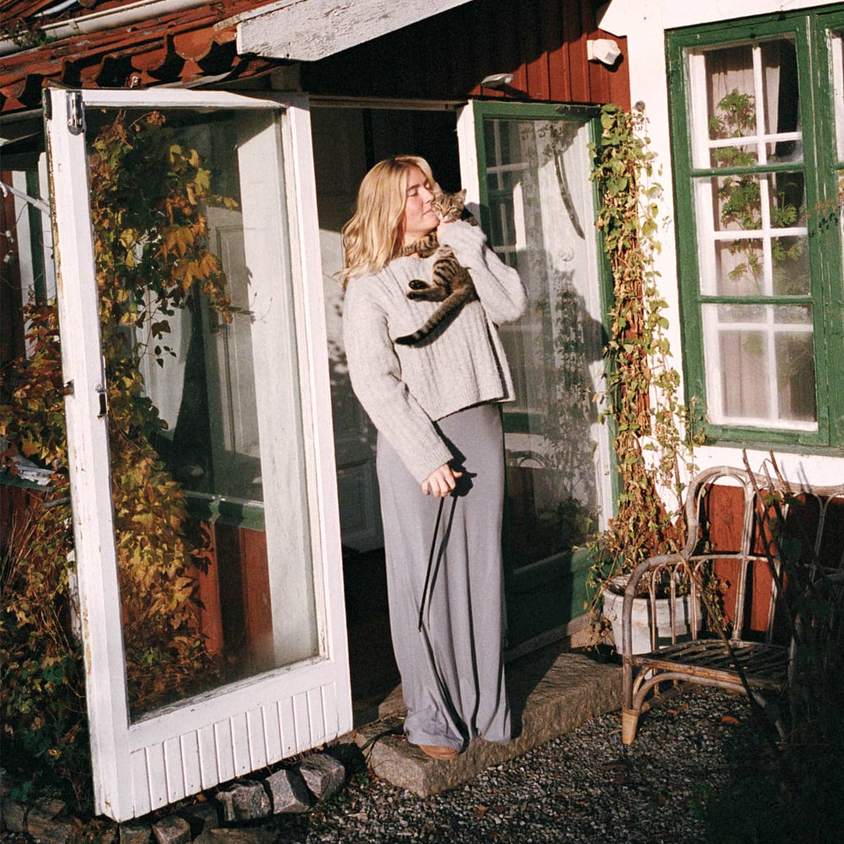 Person kramar om sin katt utanför hus