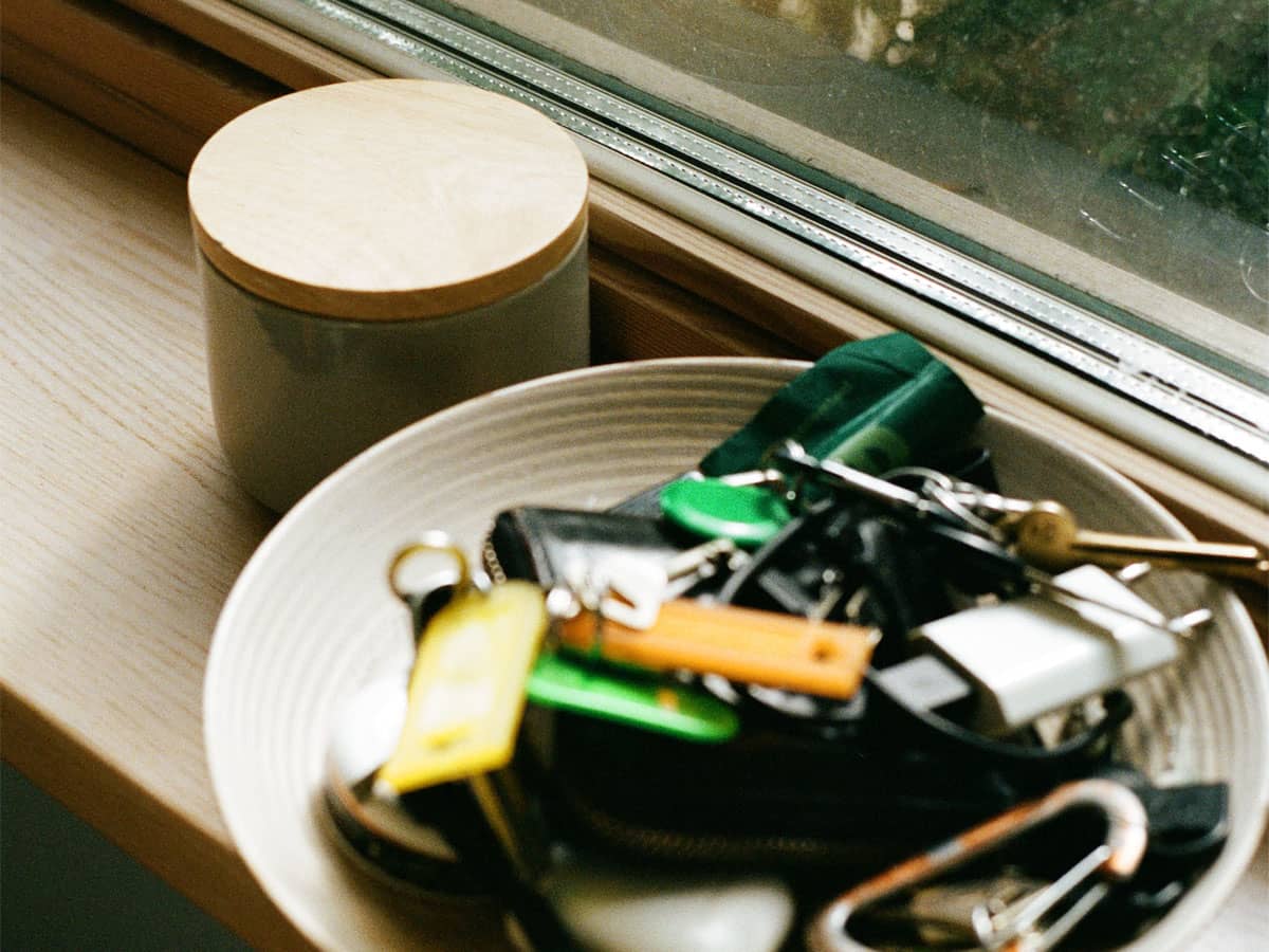 Skål med nycklar, lås och mobilladdare på fönsterbräda