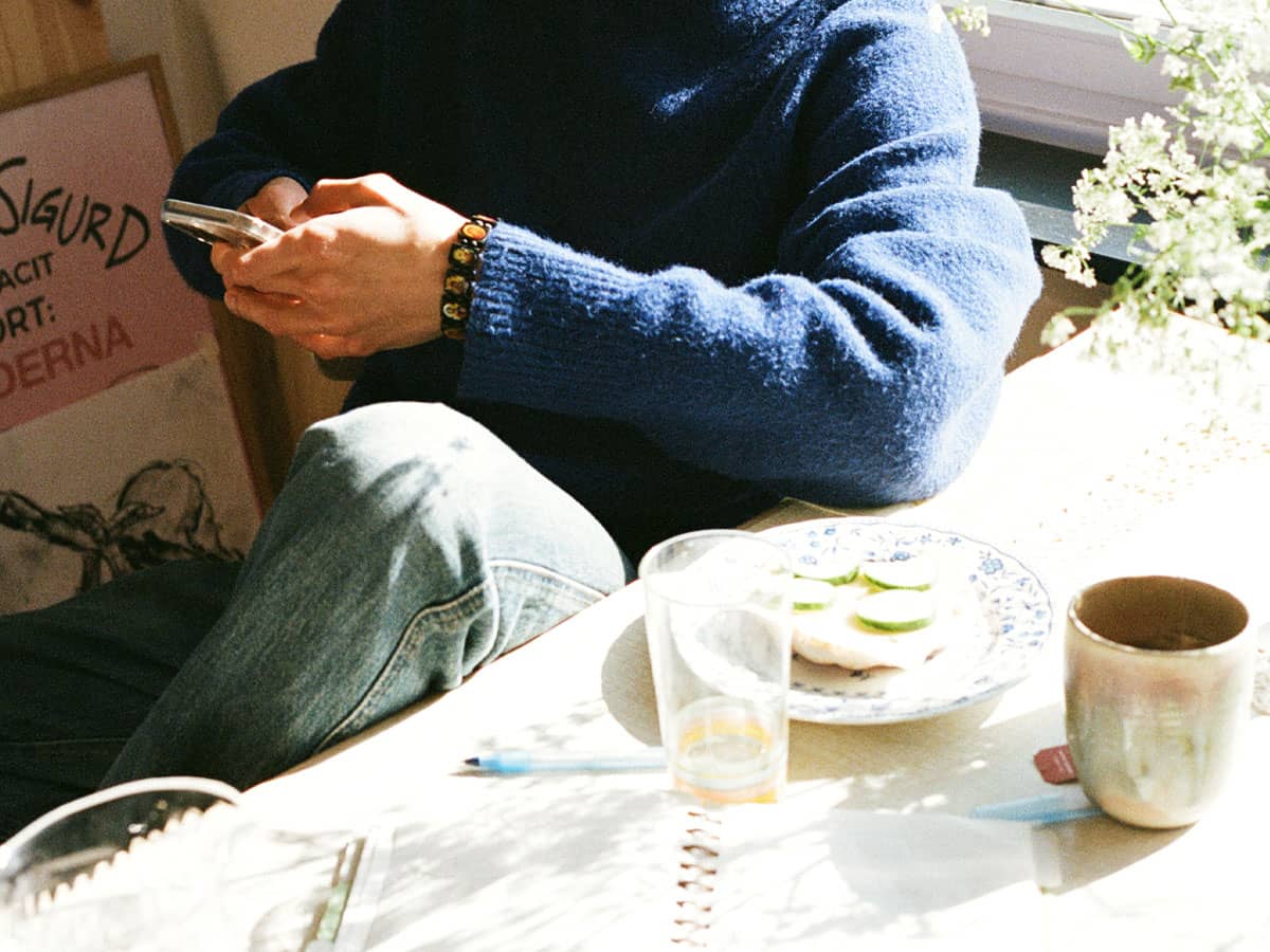 Person scrollar på mobilen vid frukostbordet