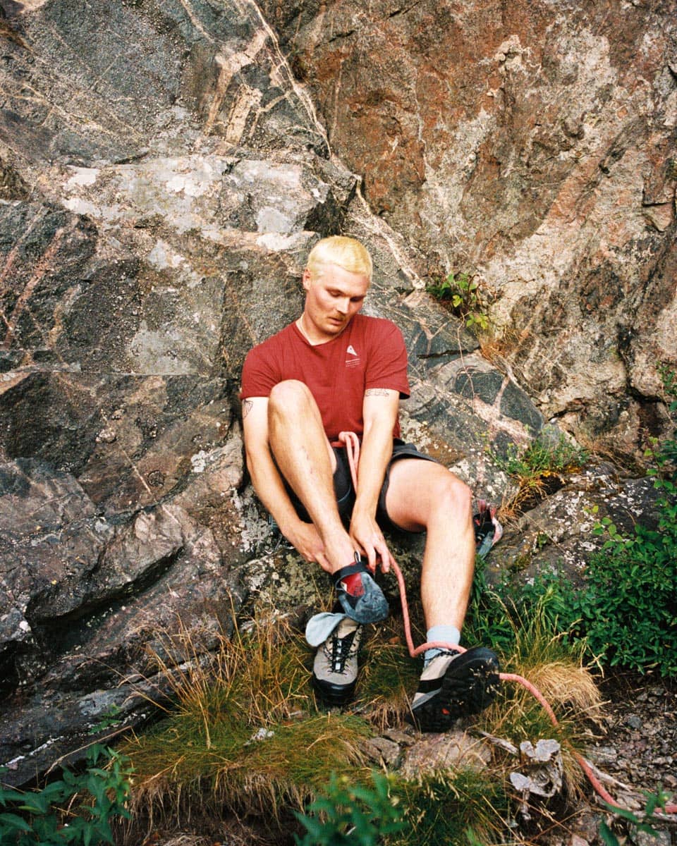 Klättrare tar på sig klätterskor vid bergsvägg